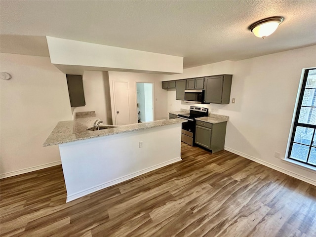3913 Longstraw Dr, Fort Worth, TX 76137 - kitchen featuring stainless steel appliances, dark wood finished floors, baseboards, a peninsula, and a textured ceiling