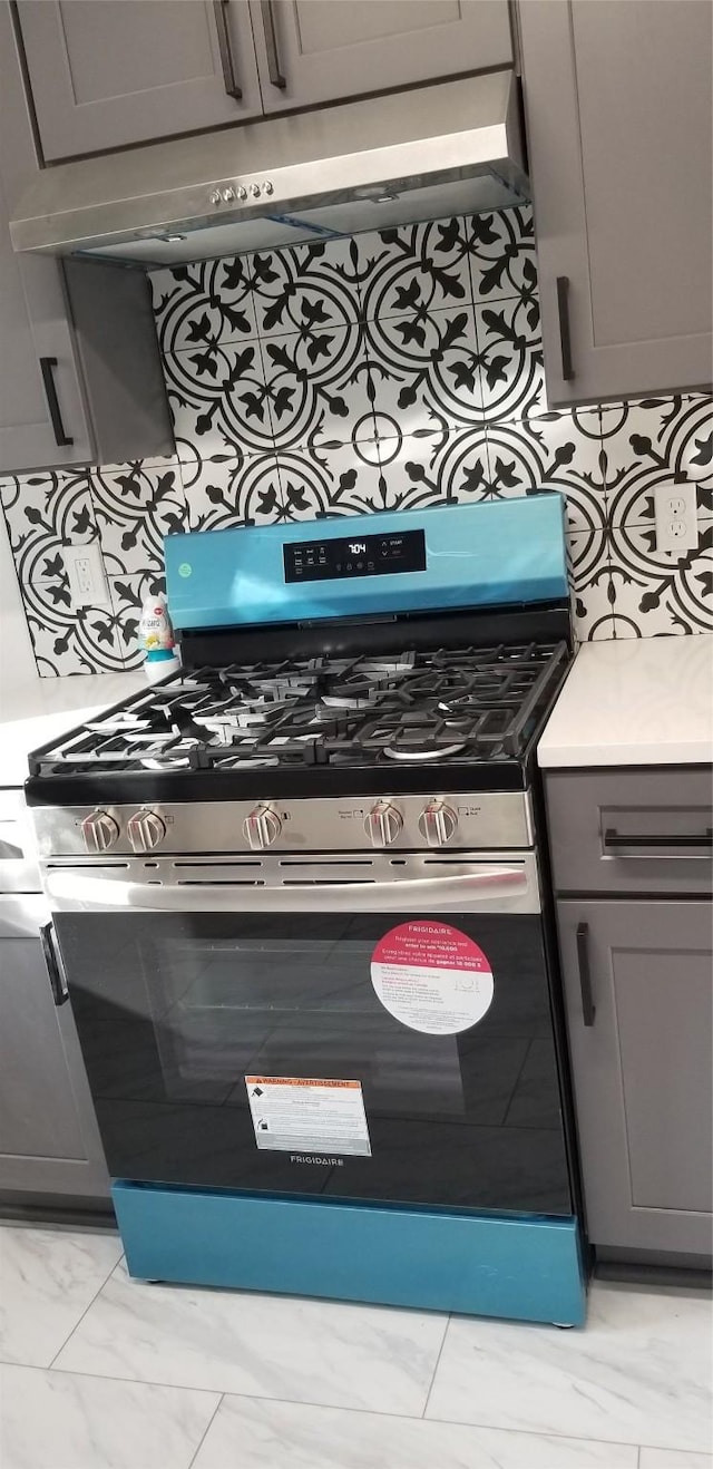412 Ellis St, Allen, TX 75002 - kitchen view of stainless steel gas range, pot filler, under cabinet range hood, gray cabinetry, and light countertops