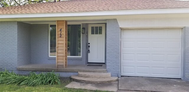 412 Ellis St, Allen, TX 75002 - view of exterior entry featuring a shingled roof, brick siding, a garage, and covered porch