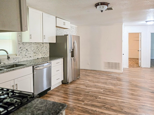 1155 Clay St, Canton, TX 75103 - kitchen featuring stainless steel appliances, white cabinets, dark wood finished floors, decorative backsplash, and a sink
