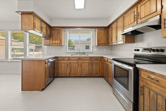 310 Naples Dr, Duncanville, TX 75116 - kitchen with stainless steel appliances, under cabinet range hood, brown cabinetry, a sink, and a peninsula