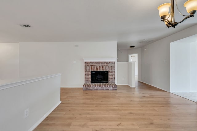 812 Piedmont Dr, Mckinney, TX 75071 - unfurnished living room with light wood-style flooring, a chandelier, a brick fireplace, and baseboards
