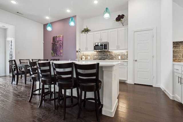 1809 13th St, Argyle, TX 76226 - kitchen with stainless steel microwave, tasteful backsplash, dark wood-type flooring, light countertops, and a kitchen breakfast bar