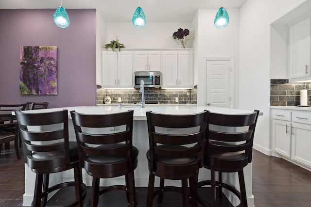 1809 13th St, Argyle, TX 76226 - kitchen with stainless steel microwave, backsplash, light countertops, a kitchen bar, and a center island with sink