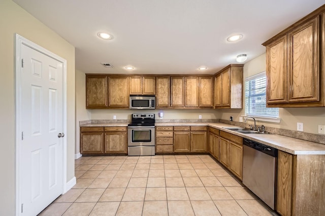 117 Parkview Dr, Saginaw, TX 76179 - kitchen featuring appliances with stainless steel finishes, a sink, brown cabinetry, light tile patterned floors, and light countertops