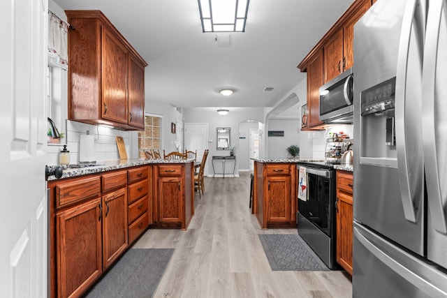 475 Maywood, Woodway, TX 76712 - kitchen featuring stainless steel appliances, a peninsula, light wood-type flooring, and light stone countertops