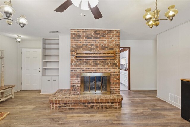 226 Hillcrest St, Sanger, TX 76266 - unfurnished living room featuring a chandelier, a brick fireplace, wood finished floors, and ceiling fan