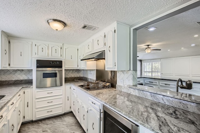 8 Canyon Ridge Dr, Fate, TX 75087 - kitchen featuring stainless steel oven, beverage cooler, under cabinet range hood, light stone countertops, and a textured ceiling