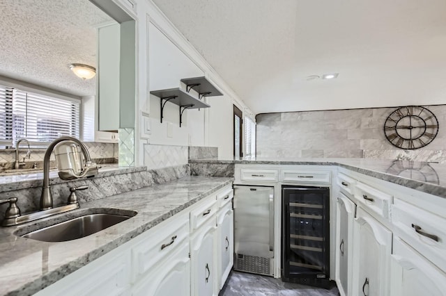 8 Canyon Ridge Dr, Fate, TX 75087 - kitchen featuring wine cooler, a sink, a textured ceiling, healthy amount of natural light, and tasteful backsplash