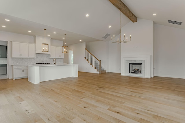 14448 Walsh, Aledo, TX 76008 - kitchen featuring open floor plan, a chandelier, beam ceiling, light wood-style floors, and decorative backsplash