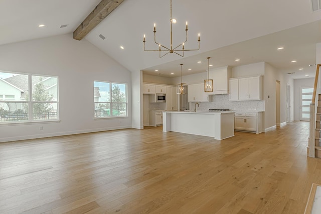 14448 Walsh, Aledo, TX 76008 - kitchen with beam ceiling, a chandelier, stainless steel microwave, an island with sink, and white cabinetry