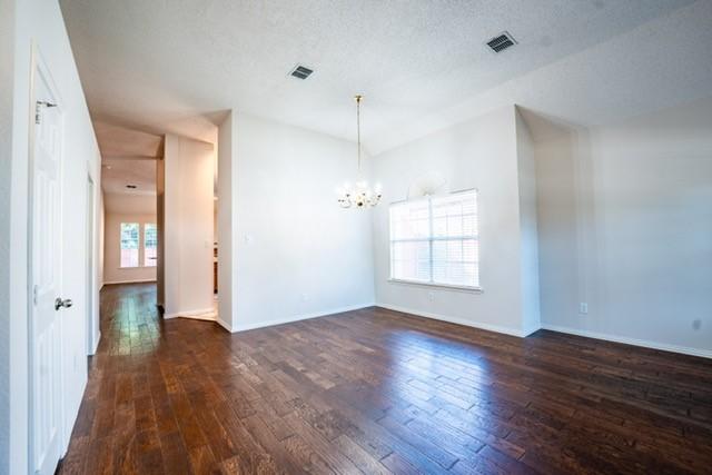 833 Tablerock Way, Lewisville, TX 75077 - empty room with dark wood finished floors, a chandelier, and baseboards