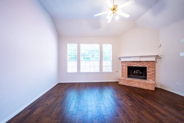 833 Tablerock Way, Lewisville, TX 75077 - unfurnished living room with vaulted ceiling, dark wood-type flooring, ceiling fan, a brick fireplace, and baseboards