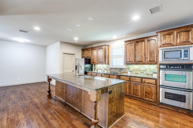 11257 Lamar Ln, Frisco, TX 75033 - kitchen featuring a sink, stainless steel appliances, dark wood-style floors, a kitchen bar, and recessed lighting
