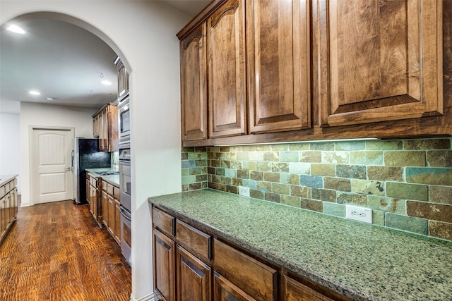 11257 Lamar Ln, Frisco, TX 75033 - kitchen with arched walkways, backsplash, appliances with stainless steel finishes, dark wood-style floors, and recessed lighting