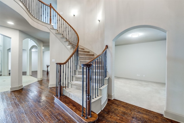 11257 Lamar Ln, Frisco, TX 75033 - stairs featuring arched walkways, wood finished floors, a towering ceiling, and baseboards