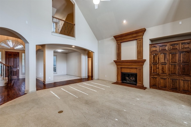 11257 Lamar Ln, Frisco, TX 75033 - unfurnished living room with carpet floors, arched walkways, high vaulted ceiling, a large fireplace, and ceiling fan