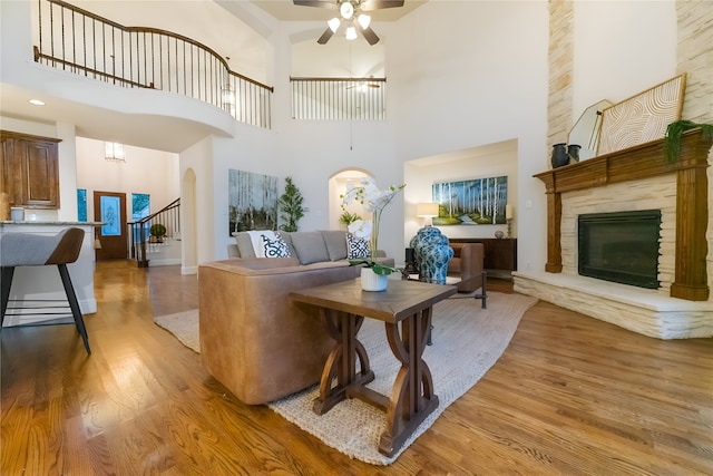 1503 Willingham Dr, Allen, TX 75013 - living room with wood finished floors, ceiling fan, a towering ceiling, arched walkways, and a stone fireplace