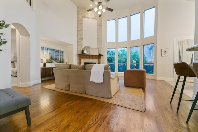 1503 Willingham Dr, Allen, TX 75013 - living area with a towering ceiling, a ceiling fan, a fireplace, wood finished floors, and arched walkways