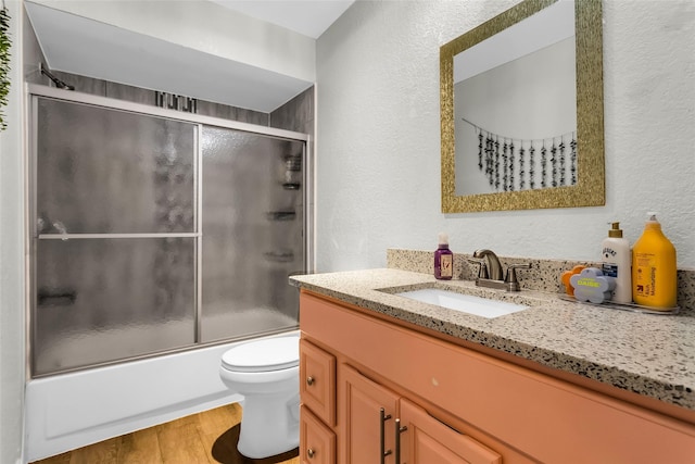 8910 Deerwood Dr, Rowlett, TX 75088 - full bath with vanity, toilet, a textured wall, wood finished floors, and combined bath / shower with glass door