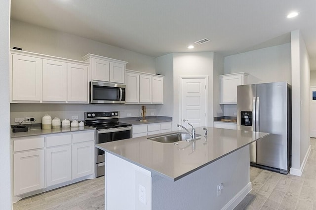 704 Griffith Park Trl, Alvarado, TX 76009 - kitchen featuring stainless steel appliances, light wood-style flooring, a sink, white cabinetry, and an island with sink