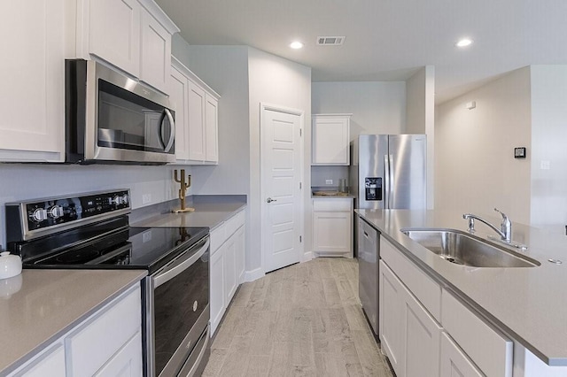 704 Griffith Park Trl, Alvarado, TX 76009 - kitchen featuring stainless steel appliances, a sink, light wood-type flooring, white cabinetry, and recessed lighting