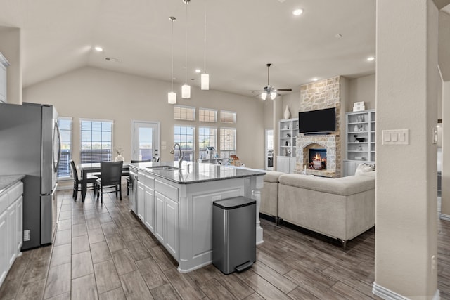 9212 Brittlebrush Trl, Fort Worth, TX 76177 - kitchen featuring stainless steel appliances, ceiling fan, a sink, a fireplace, and white cabinets