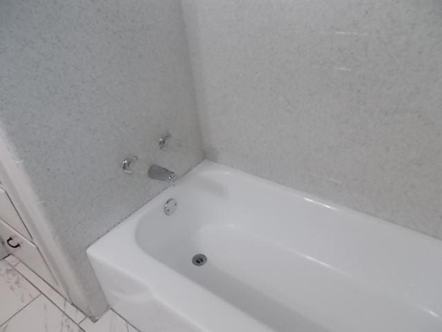 601 N 38th St, Corsicana, TX 75110 - bathroom featuring marble look tile flooring and a bath