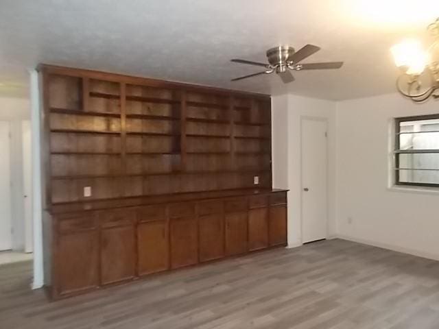 601 N 38th St, Corsicana, TX 75110 - unfurnished living room featuring a chandelier, light wood-style floors, a ceiling fan, and baseboards