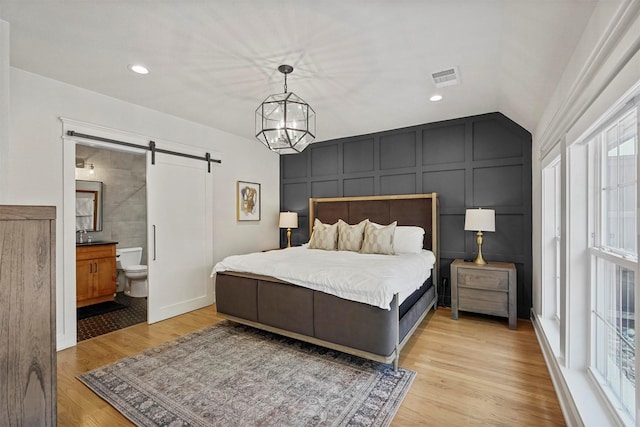 435 Allison Dr, Dallas, TX 75208 - bedroom featuring a barn door, a decorative wall, light wood-style flooring, a chandelier, and ensuite bathroom
