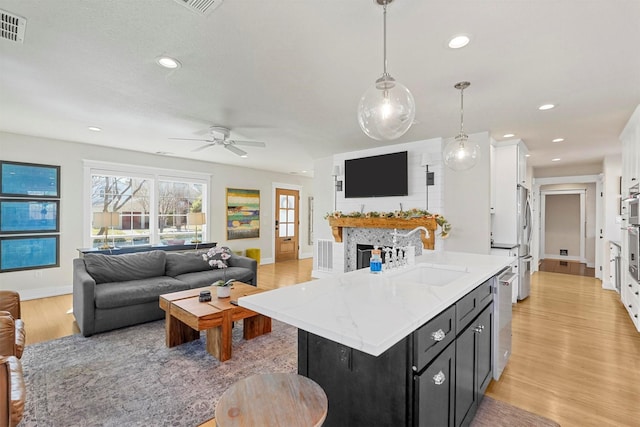 435 Allison Dr, Dallas, TX 75208 - kitchen featuring a sink, open floor plan, dark cabinets, light wood-style floors, and stainless steel appliances