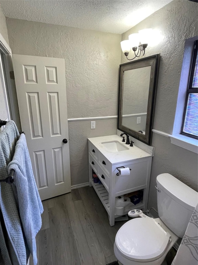 322 Cherry St, Weatherford, TX 76086 - half bathroom with a textured wall, a textured ceiling, wood finished floors, vanity, and toilet