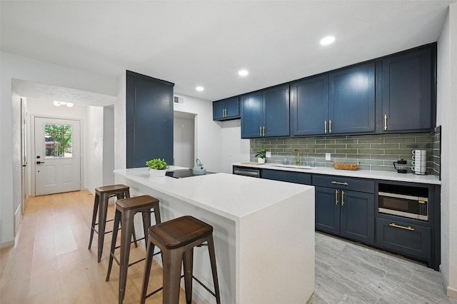 7201 Harwick Ln, North Richland Hills, TX 76182 - kitchen featuring blue cabinets, a sink, a kitchen breakfast bar, light wood finished floors, and stainless steel microwave
