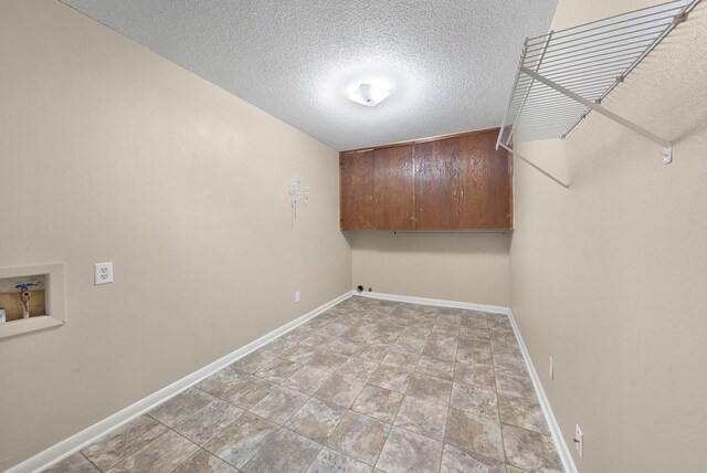1804 Posey Ln, Sulphur Springs, TX 75482 - laundry area with washer hookup, baseboards, a textured ceiling, cabinet space, and stone finish floors
