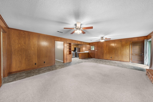 1804 Posey Ln, Sulphur Springs, TX 75482 - unfurnished living room with a ceiling fan, wood walls, light carpet, a textured ceiling, and baseboards