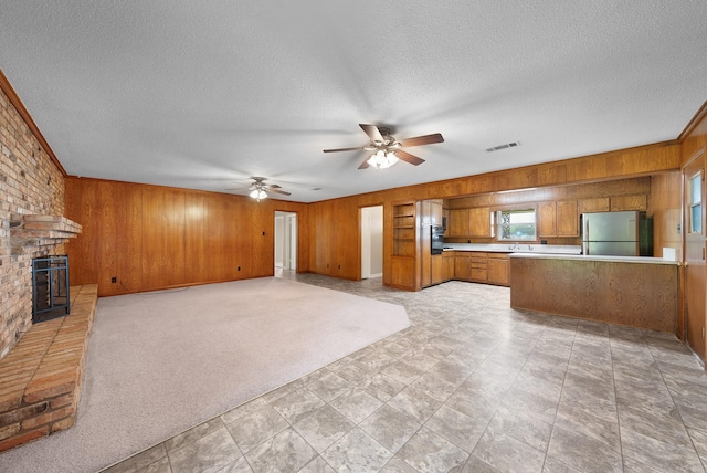 1804 Posey Ln, Sulphur Springs, TX 75482 - unfurnished living room with wooden walls, a textured ceiling, a brick fireplace, a ceiling fan, and a sink
