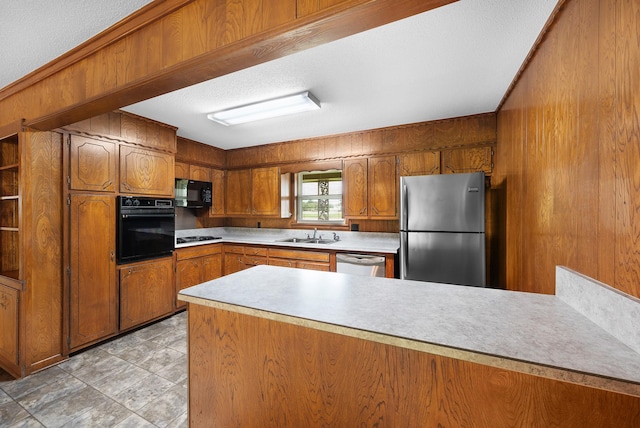 1804 Posey Ln, Sulphur Springs, TX 75482 - kitchen with black appliances, brown cabinets, a peninsula, a sink, and light countertops