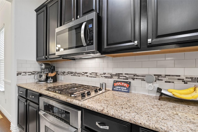 12341 Payne St, Frisco, TX 75033 - kitchen with appliances with stainless steel finishes, dark cabinetry, and tasteful backsplash