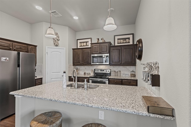 2101 Swenson Ranch Trl, Fort Worth, TX 76134 - kitchen featuring appliances with stainless steel finishes, a sink, dark brown cabinets, backsplash, and a breakfast bar