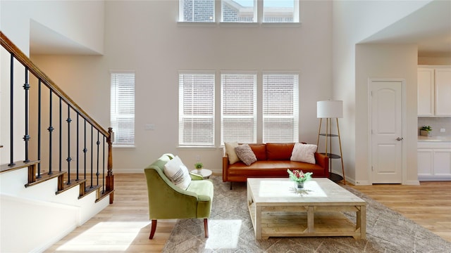 2753 Henson Ln, Garland, TX 75040 - living room featuring a towering ceiling, light wood-type flooring, plenty of natural light, stairs, and baseboards