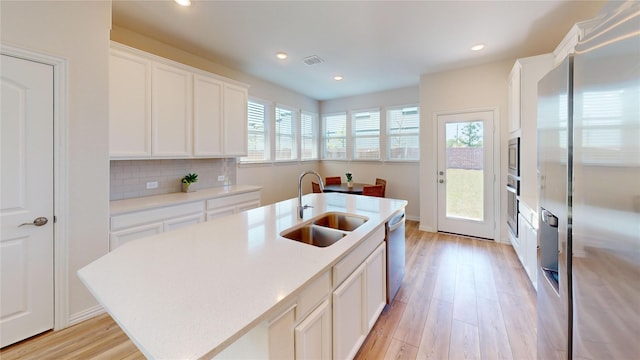 2753 Henson Ln, Garland, TX 75040 - kitchen featuring appliances with stainless steel finishes, a sink, light wood-style floors, light countertops, and white cabinets