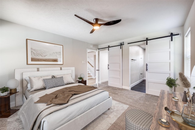 3414 Janlyn Ln, Farmers Branch, TX 75234 - carpeted bedroom with a barn door, baseboards, a textured ceiling, and ceiling fan