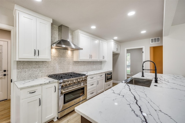 3414 Janlyn Ln, Farmers Branch, TX 75234 - kitchen with wall chimney range hood, high end range, a sink, light stone countertops, and light wood finished floors