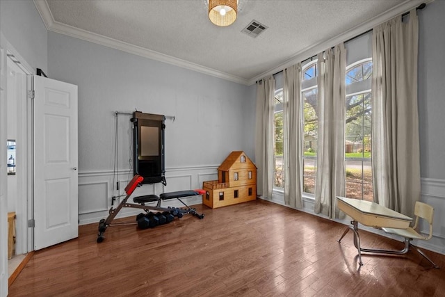 9505 Lost Trails Dr, Waco, TX 76712 - workout area with ornamental molding, wood finished floors, a textured ceiling, a decorative wall, and a wainscoted wall