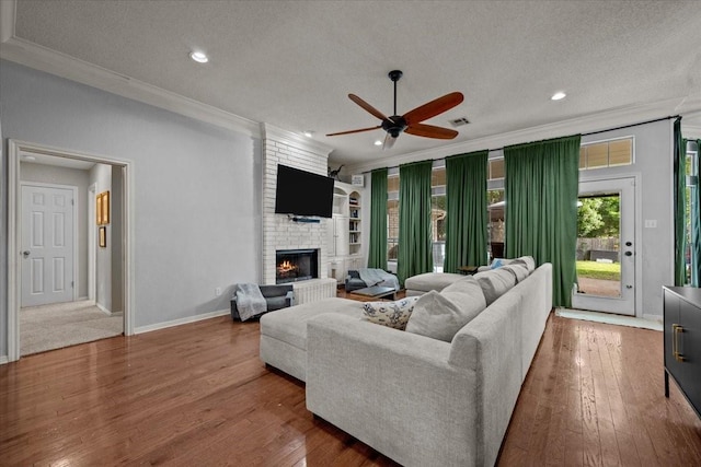 9505 Lost Trails Dr, Waco, TX 76712 - living room with crown molding, a textured ceiling, a ceiling fan, a fireplace, and wood finished floors