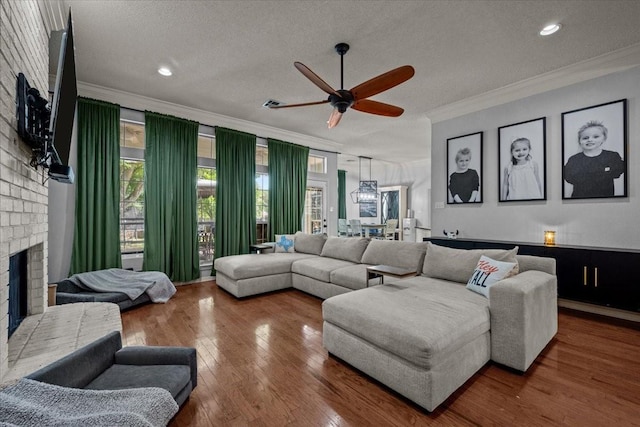 9505 Lost Trails Dr, Waco, TX 76712 - living area with ornamental molding, a brick fireplace, a textured ceiling, a ceiling fan, and wood finished floors