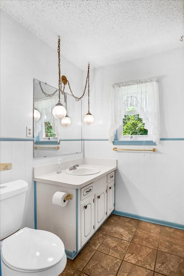 880 S Fm 779, Emory, TX 75440 - half bathroom with vanity, a textured ceiling, toilet, and wainscoting