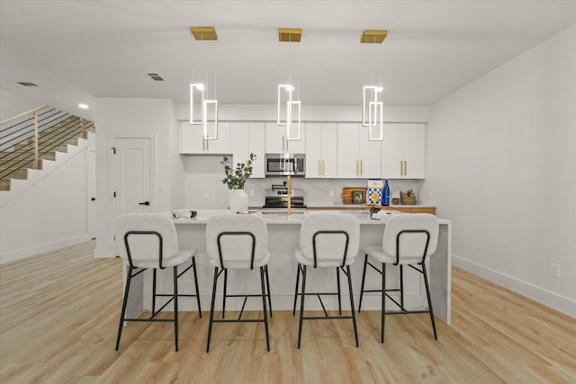 1336 Compton St, Dallas, TX 75203 - kitchen featuring appliances with stainless steel finishes, white cabinetry, baseboards, and light wood finished floors