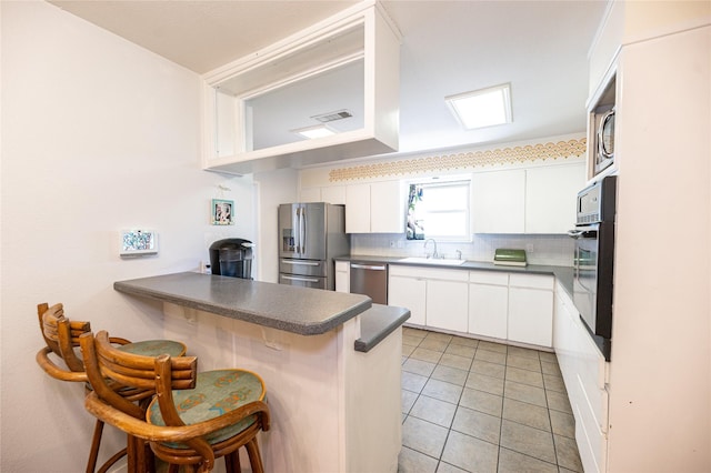 4458 Cardiff Ave, Fort Worth, TX 76133 - kitchen with appliances with stainless steel finishes, a kitchen breakfast bar, dark countertops, backsplash, and a sink