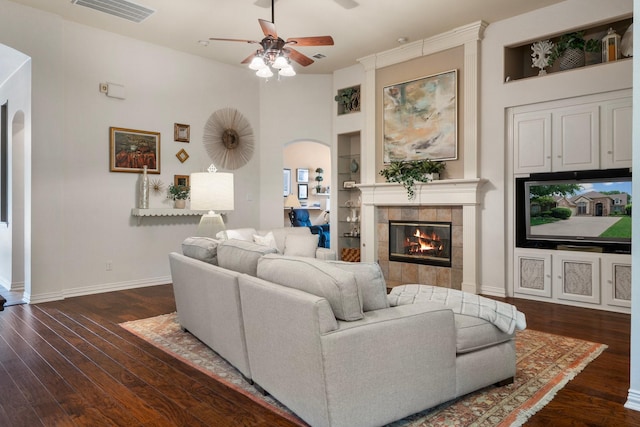 1869 Rio Blanco Dr, Frisco, TX 75033 - living room featuring a tiled fireplace, a ceiling fan, baseboards, wood finished floors, and arched walkways